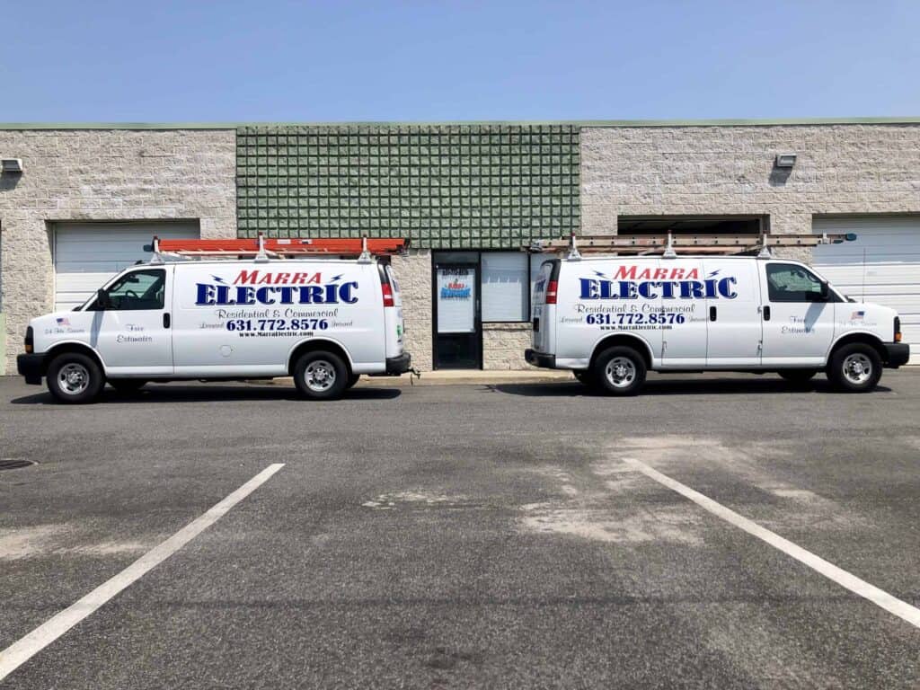 Two Marra Electric service vans with ladders parked in front of a commercial building with garage doors in Suffolk County, NY.